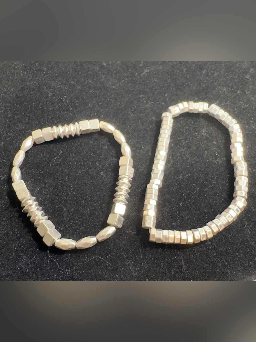 Two elastic beaded bracelets featuring silver-toned, geometric and metallic bead